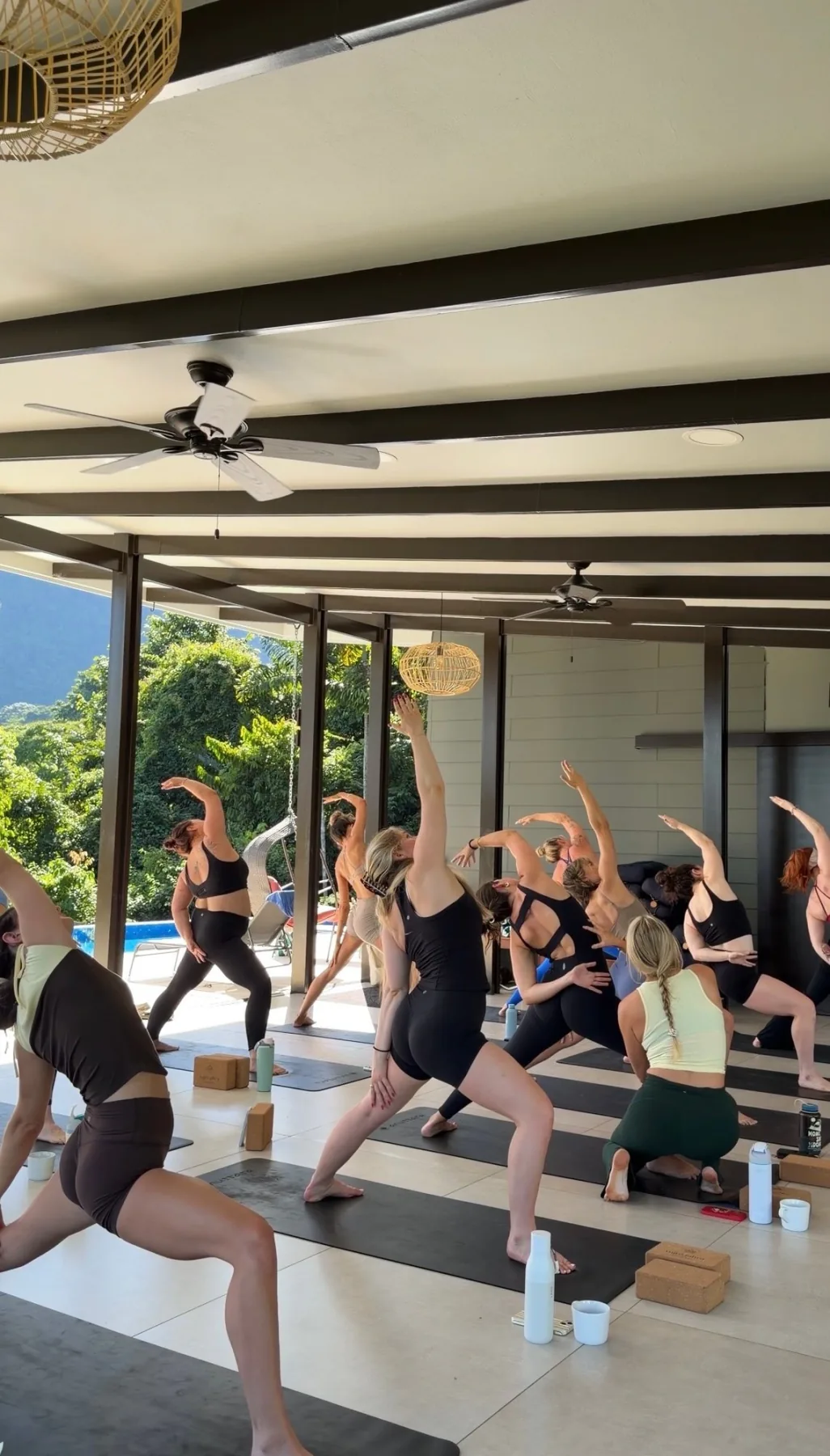 Yoga retreat group reaching upward during an open-air class
